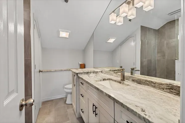 a bathroom with a granite countertop sink a toilet and a mirror