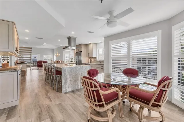 a kitchen with stainless steel appliances kitchen island granite countertop a table chairs refrigerator and a sink