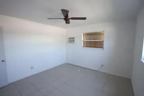 an empty room with a window and a ceiling fan