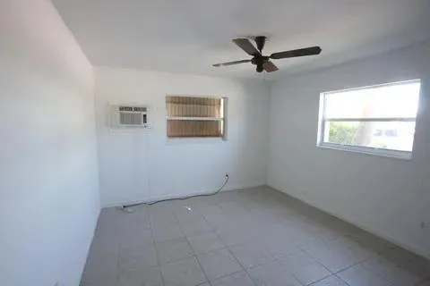 an empty room with windows and ceiling fan