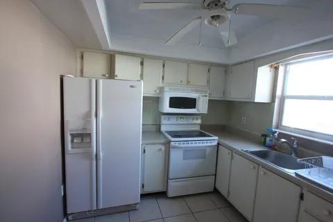 1050 East Sample Road, Unit 101 Pompano Beach, FL 33064 - Photo 5 of 19 a kitchen with a refrigerator sink and cabinets