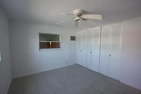 an empty room with a fan & a window