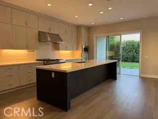a kitchen with stainless steel appliances granite countertop a sink a stove and a wooden floors