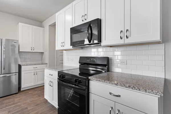 a kitchen with granite countertop white cabinets and black appliances