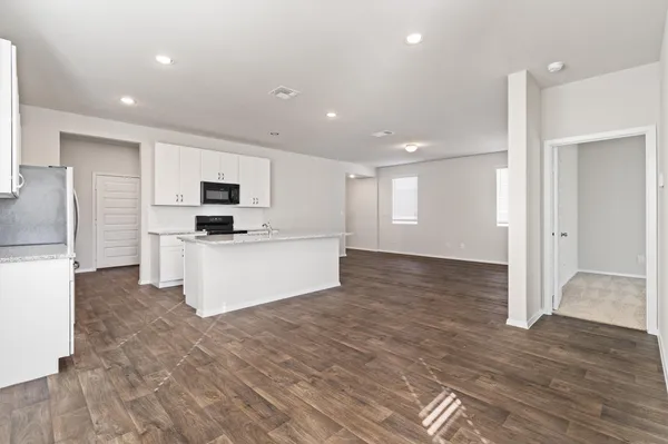 a large white kitchen with kitchen island a stove a sink dishwasher and a refrigerator with wooden floor