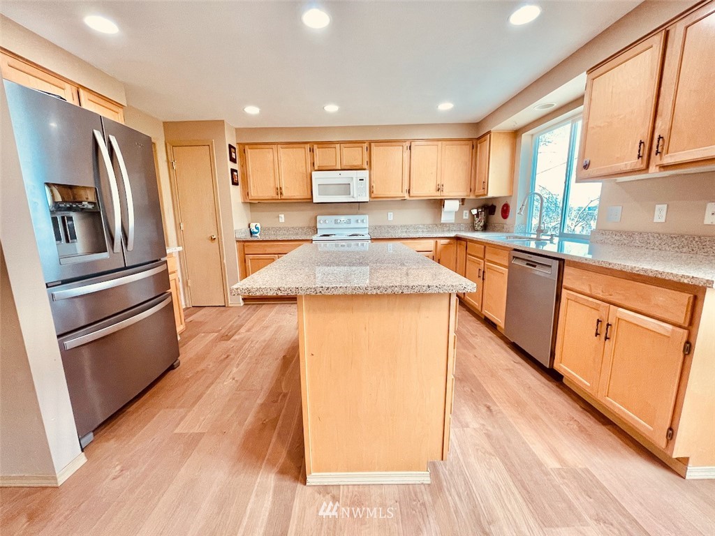 502 South 53rd Place Renton, WA 98055 - Photo 4 of 23 a kitchen with stainless steel appliances granite countertop a refrigerator a sink dishwasher a stove and white countertops with wooden floor