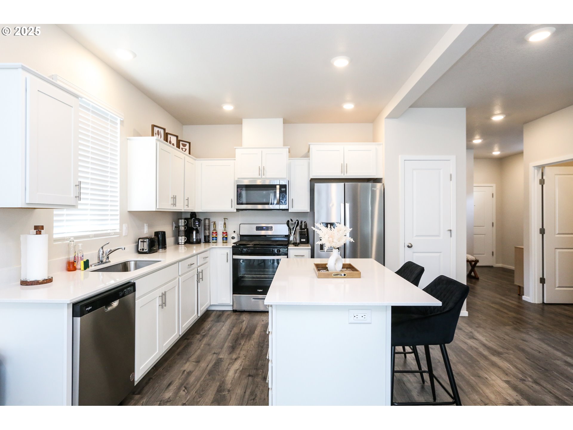 2685 V Street Springfield, OR 97477 - Photo 9 of 22 a open kitchen with stainless steel appliances kitchen island granite countertop a stove a sink a refrigerator white cabinets and wooden floor