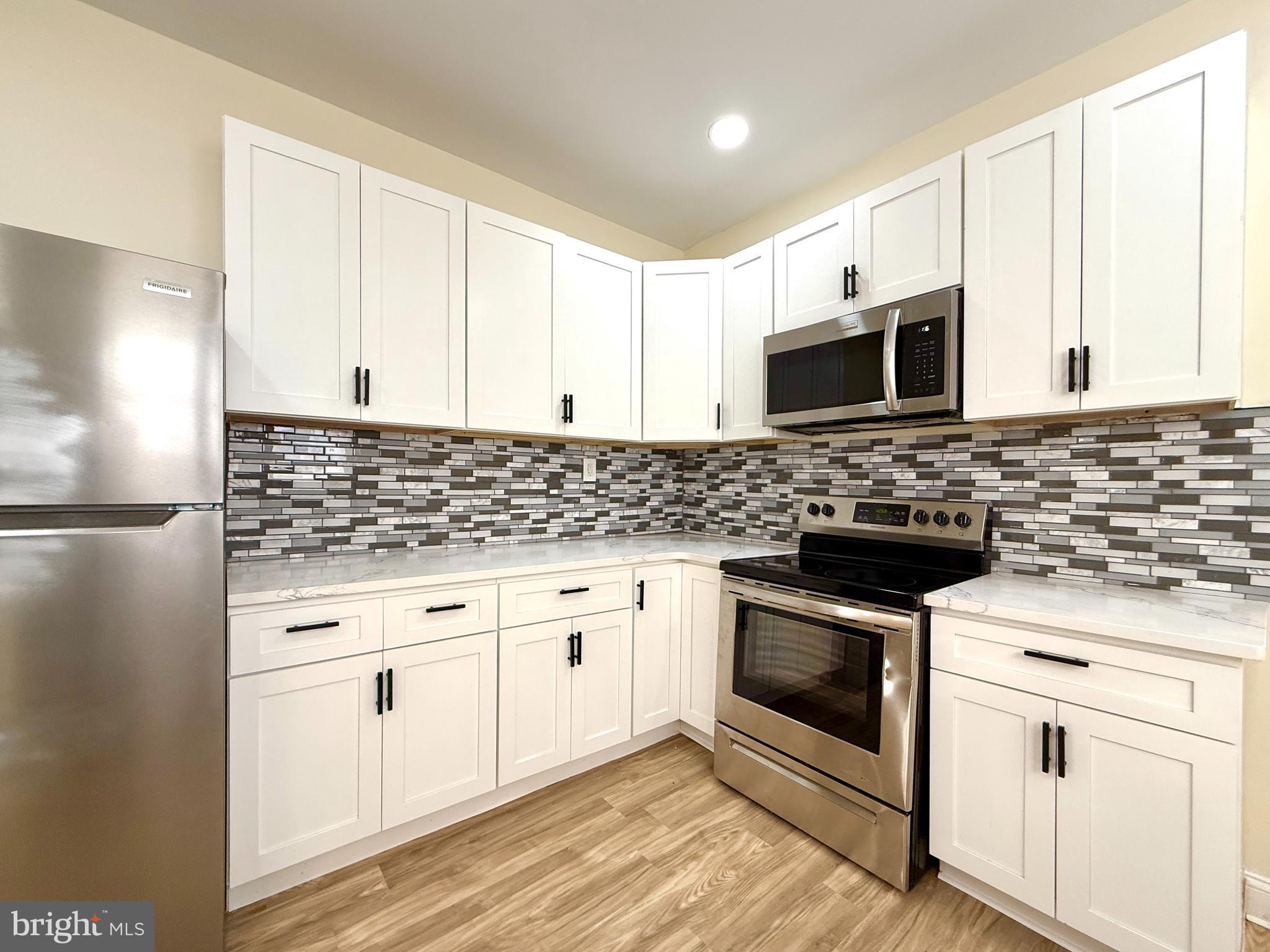 2913 West 6th Street Chester, PA 19013 - Photo 10 of 20 a kitchen with granite countertop white cabinets and stainless steel appliances