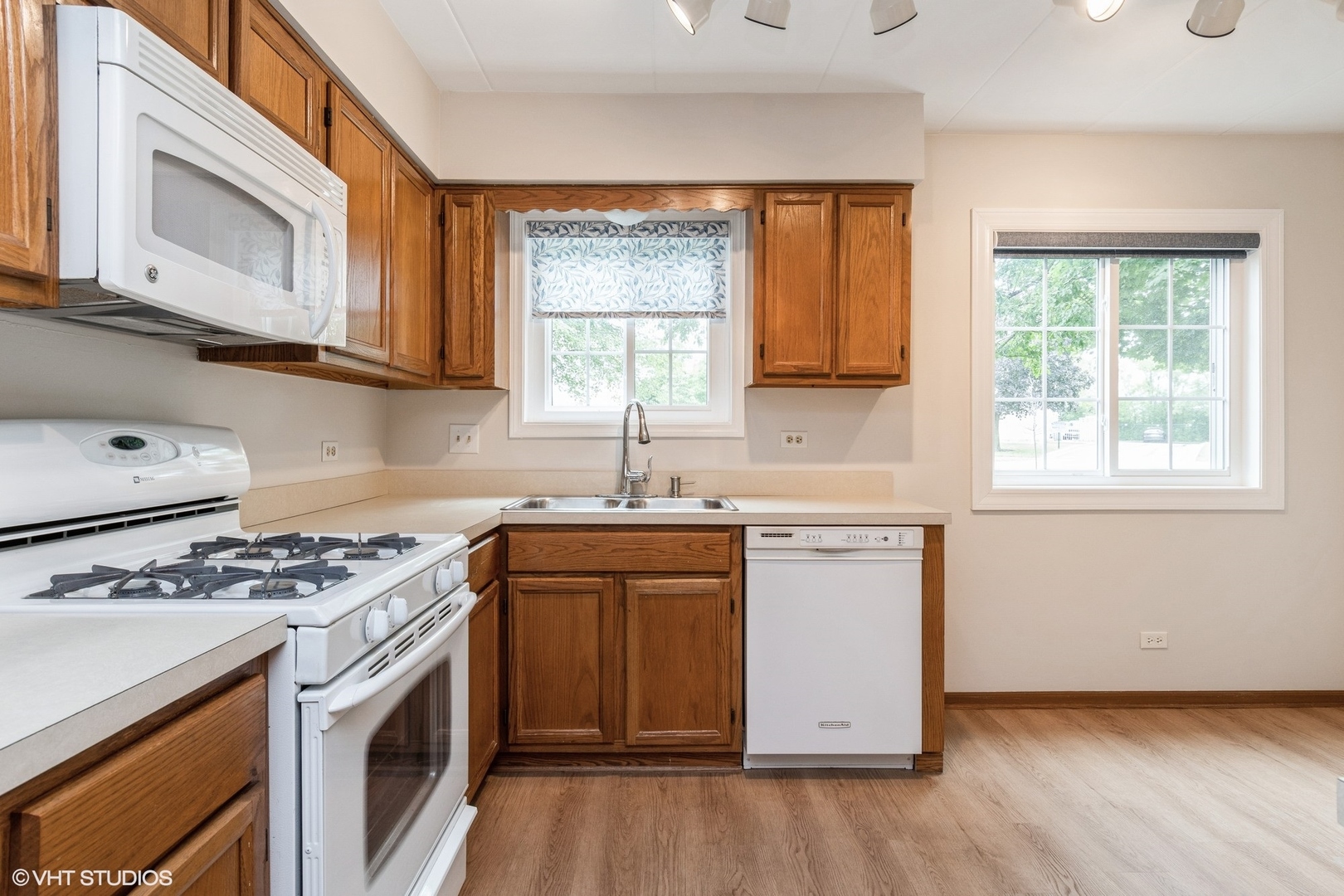 1258 Chalet Road, Unit 101 Naperville, IL 60563 - Photo 7 of 22 a kitchen with granite countertop a stove a sink and dishwasher with wooden floor