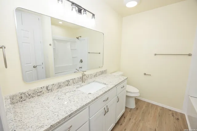 a bathroom with a granite countertop sink a toilet and shower