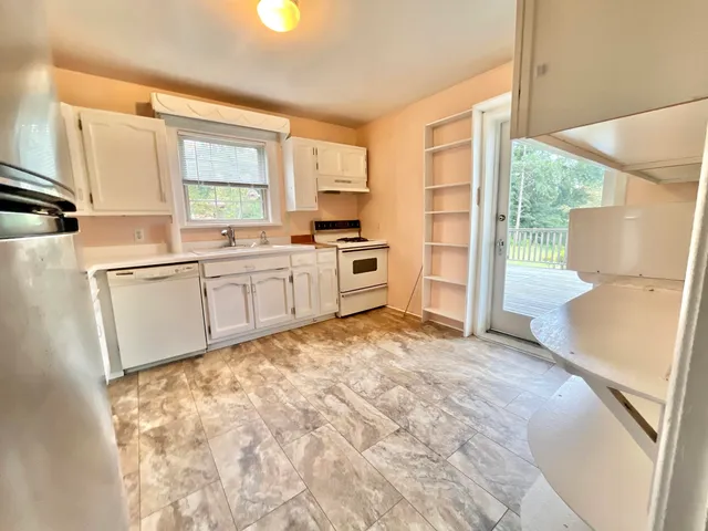 a large white kitchen with granite countertop a sink and a stove