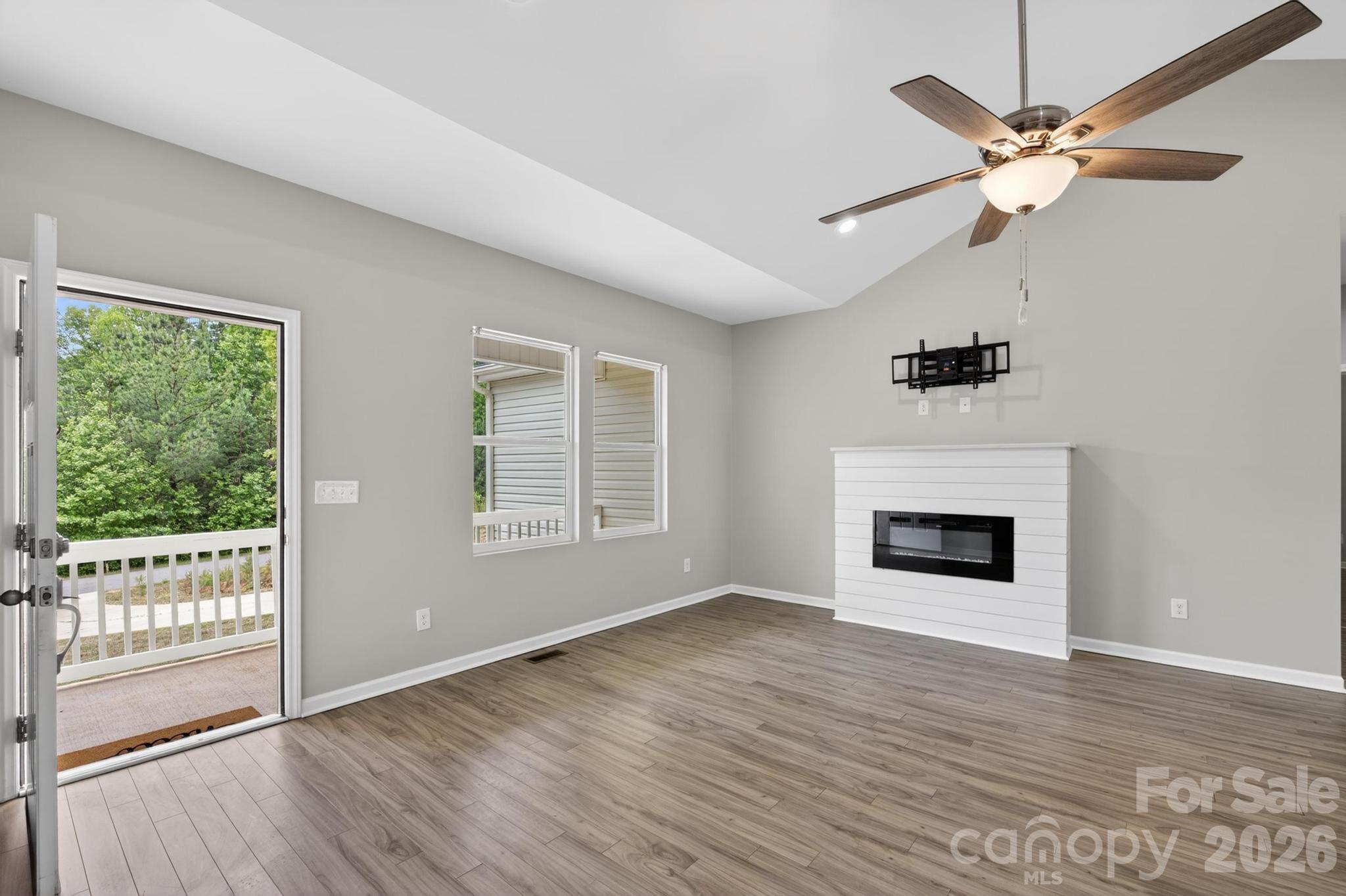 2119 South Road Morganton, NC 28655 - Photo 10 of 47 an empty room with windows a fireplace a ceiling fan and wooden floor