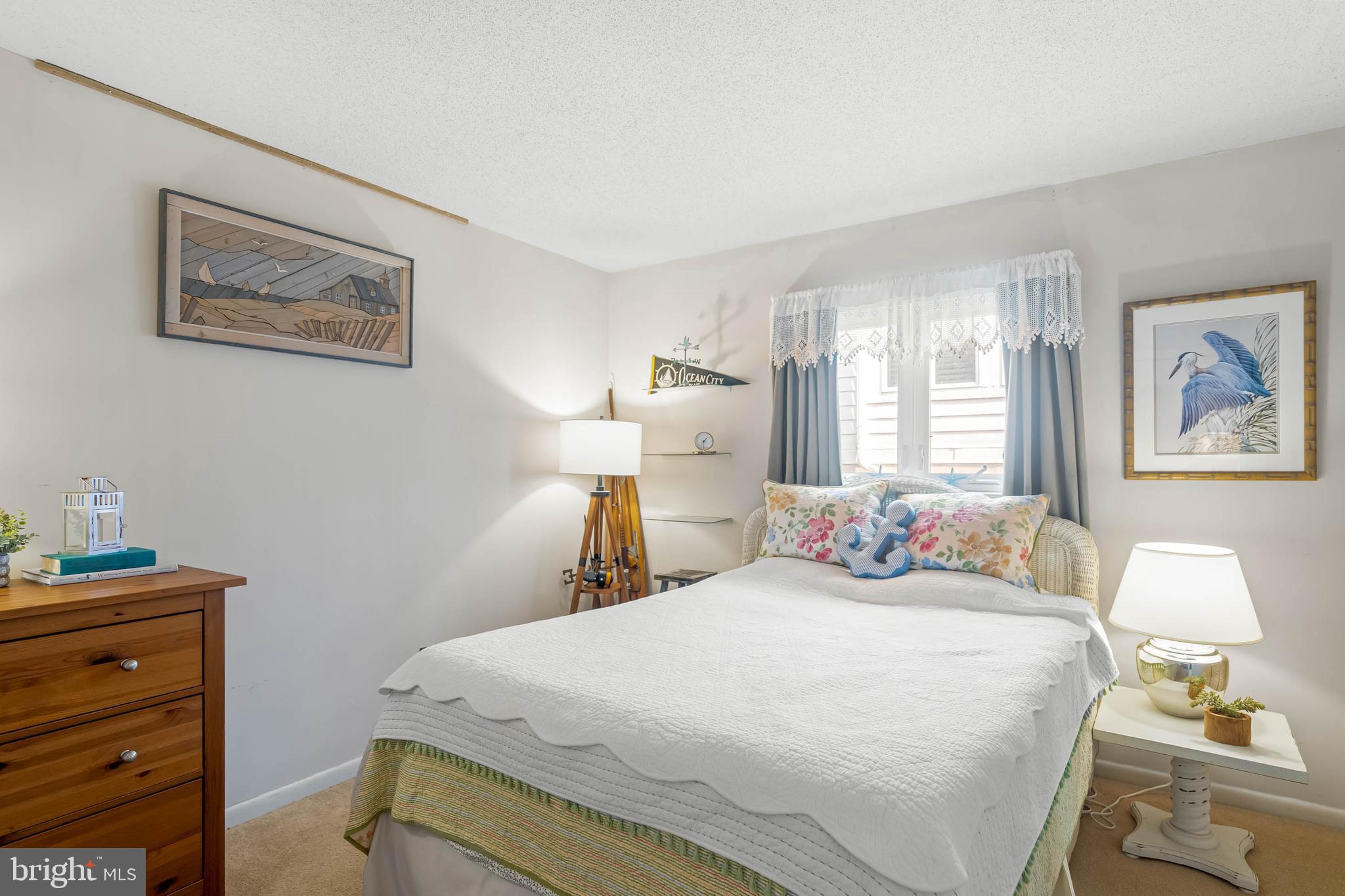 11 144th Street, Unit 102 Ocean City, MD 21842 - Photo 11 of 27 a bedroom with a bed and a lamp on dresser