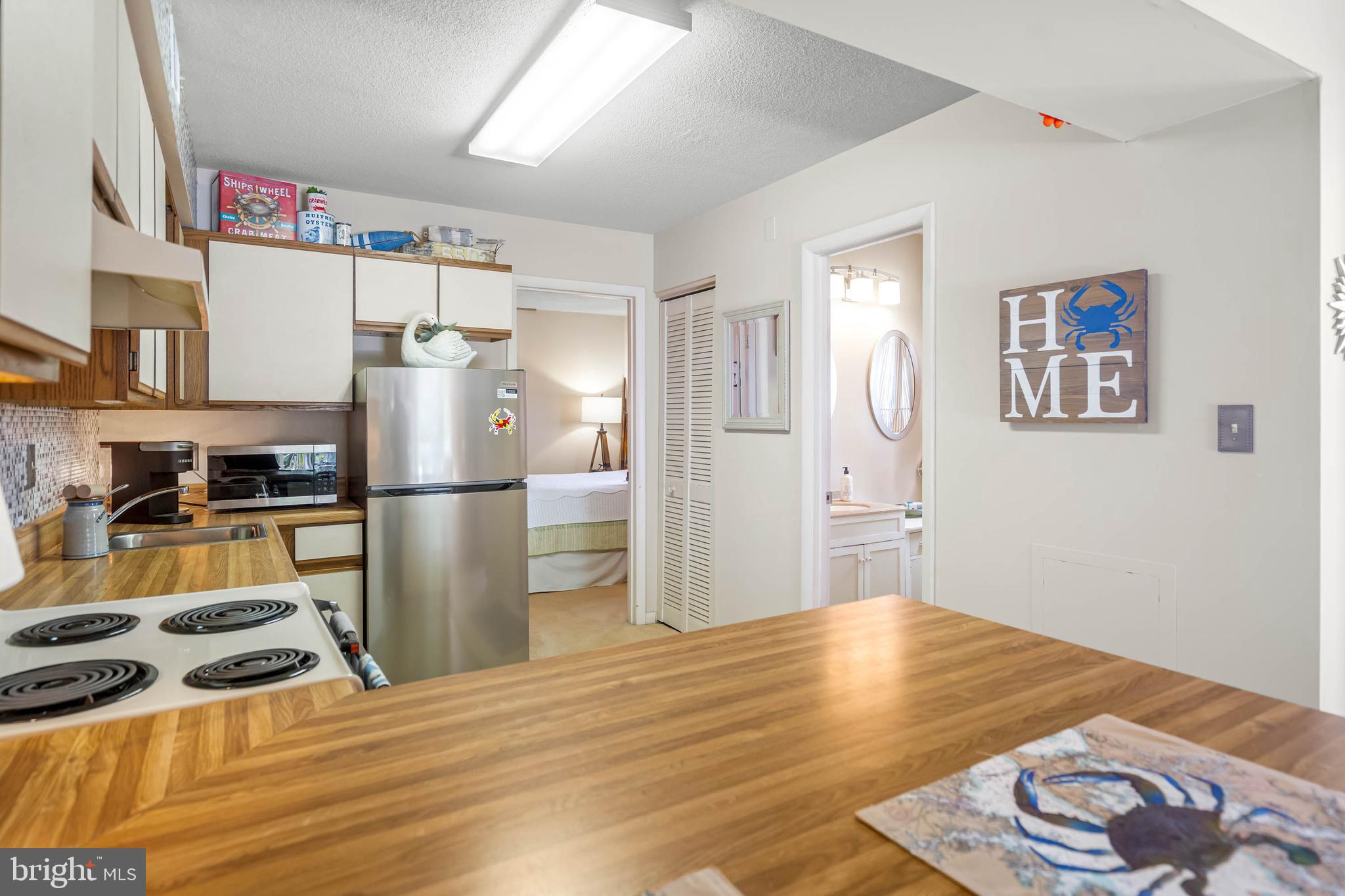 11 144th Street, Unit 102 Ocean City, MD 21842 - Photo 7 of 27 a kitchen with stainless steel appliances granite countertop a refrigerator a stove and a sink with wooden floor
