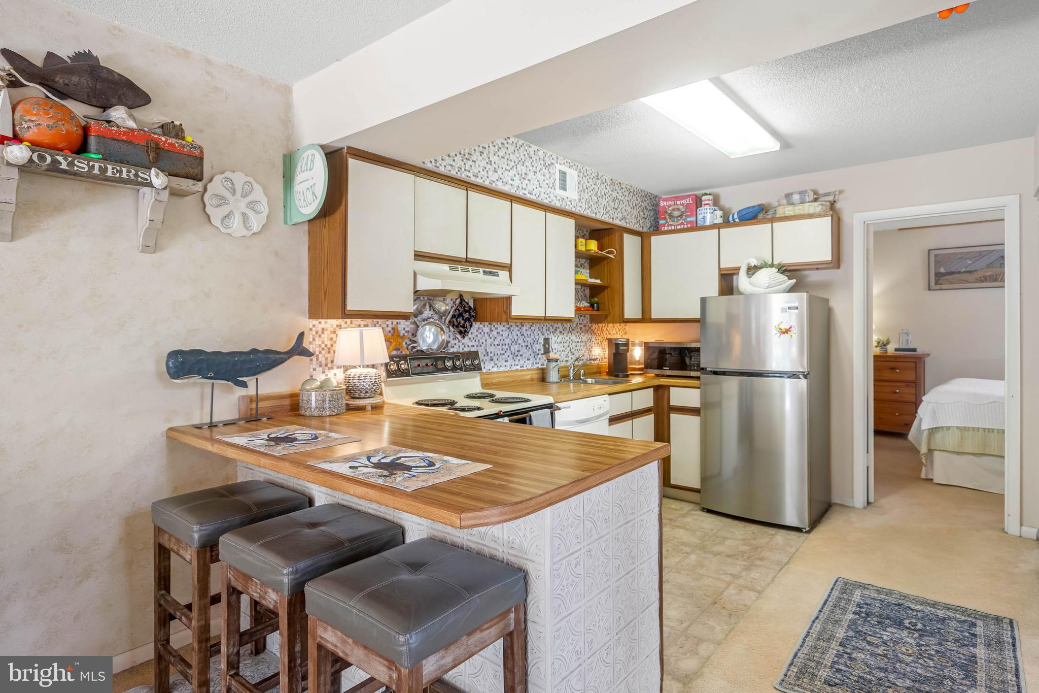 11 144th Street, Unit 102 Ocean City, MD 21842 - Photo 8 of 27 a kitchen with a refrigerator a stove and a dining table