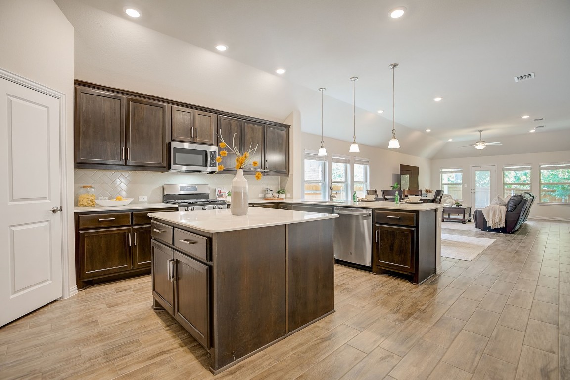a kitchen with stainless steel appliances kitchen island a stove a sink a refrigerator and a oven