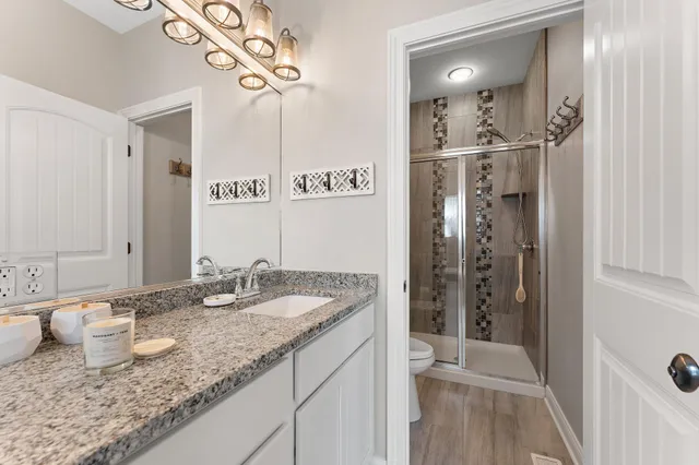 a bathroom with a granite countertop sink a mirror and shower