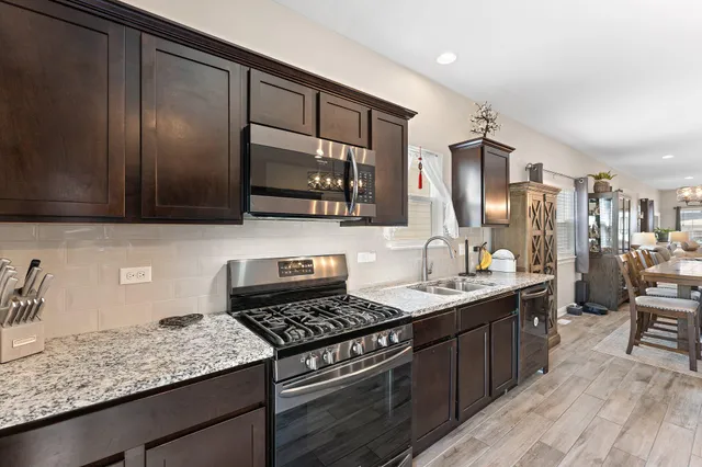 a kitchen with stainless steel appliances granite countertop a stove a sink dishwasher and microwave oven