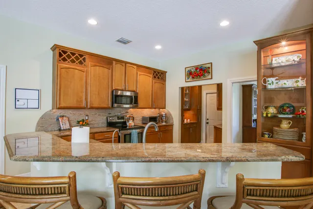 a kitchen with kitchen island granite countertop a sink cabinets and stainless steel appliances