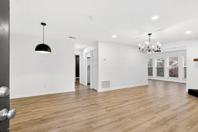 a view of an empty room with kitchen and chandelier fan