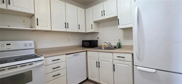 a kitchen with granite countertop white cabinets and white appliances