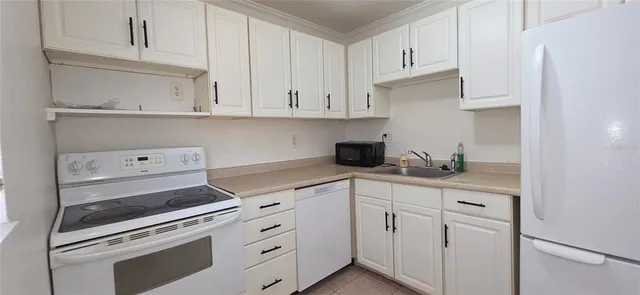 a kitchen with white cabinets and sink