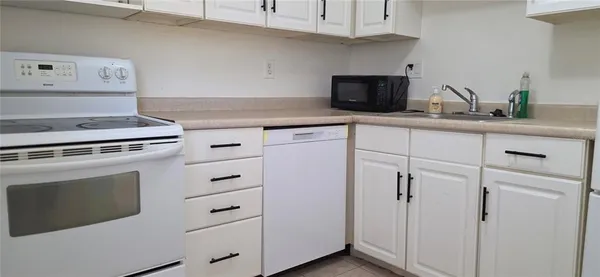 a kitchen with white cabinets and appliances