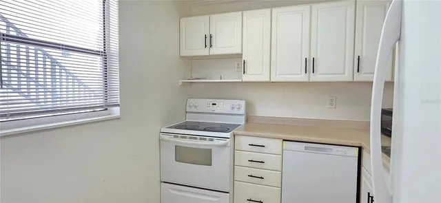 a kitchen with white cabinets and white appliances
