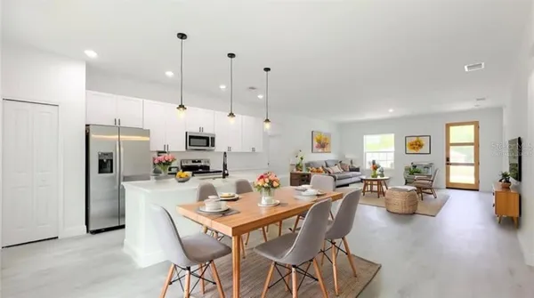 a view of a dining room and livingroom with furniture wooden floor kitchen view and living room view