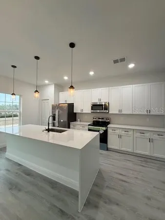 a large kitchen with kitchen island a stove a sink a refrigerator and a granite counter top