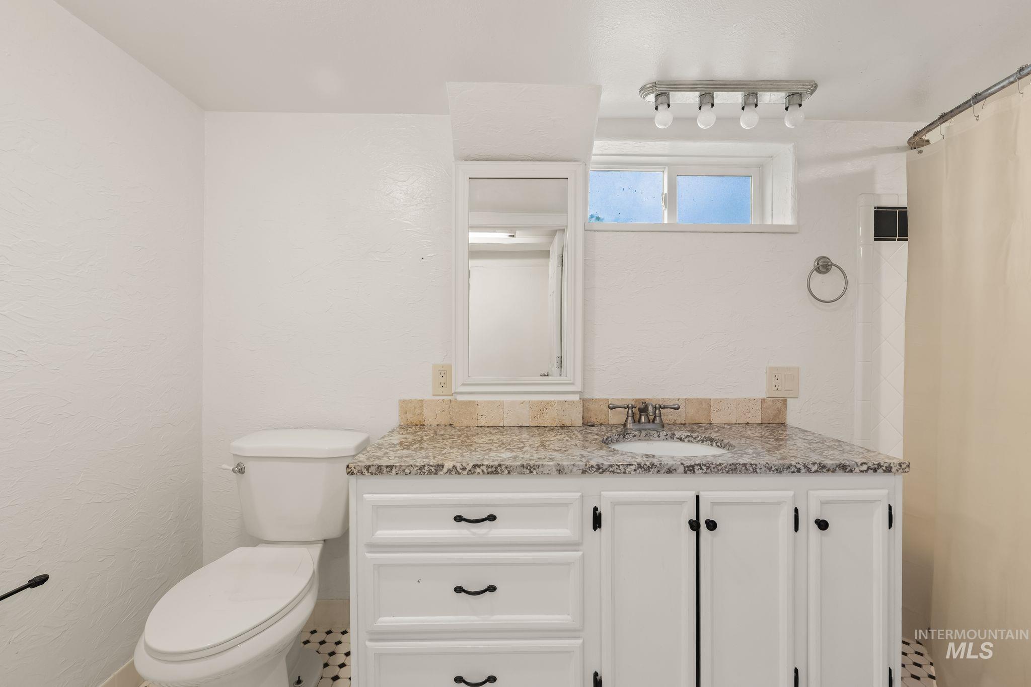 928 3rd Street Clarkston, WA 99403 - Photo 27 of 44 Bathroom featuring a white vanity with a speckled countertop, a built-in sink, and white cabinetry with dark hardware