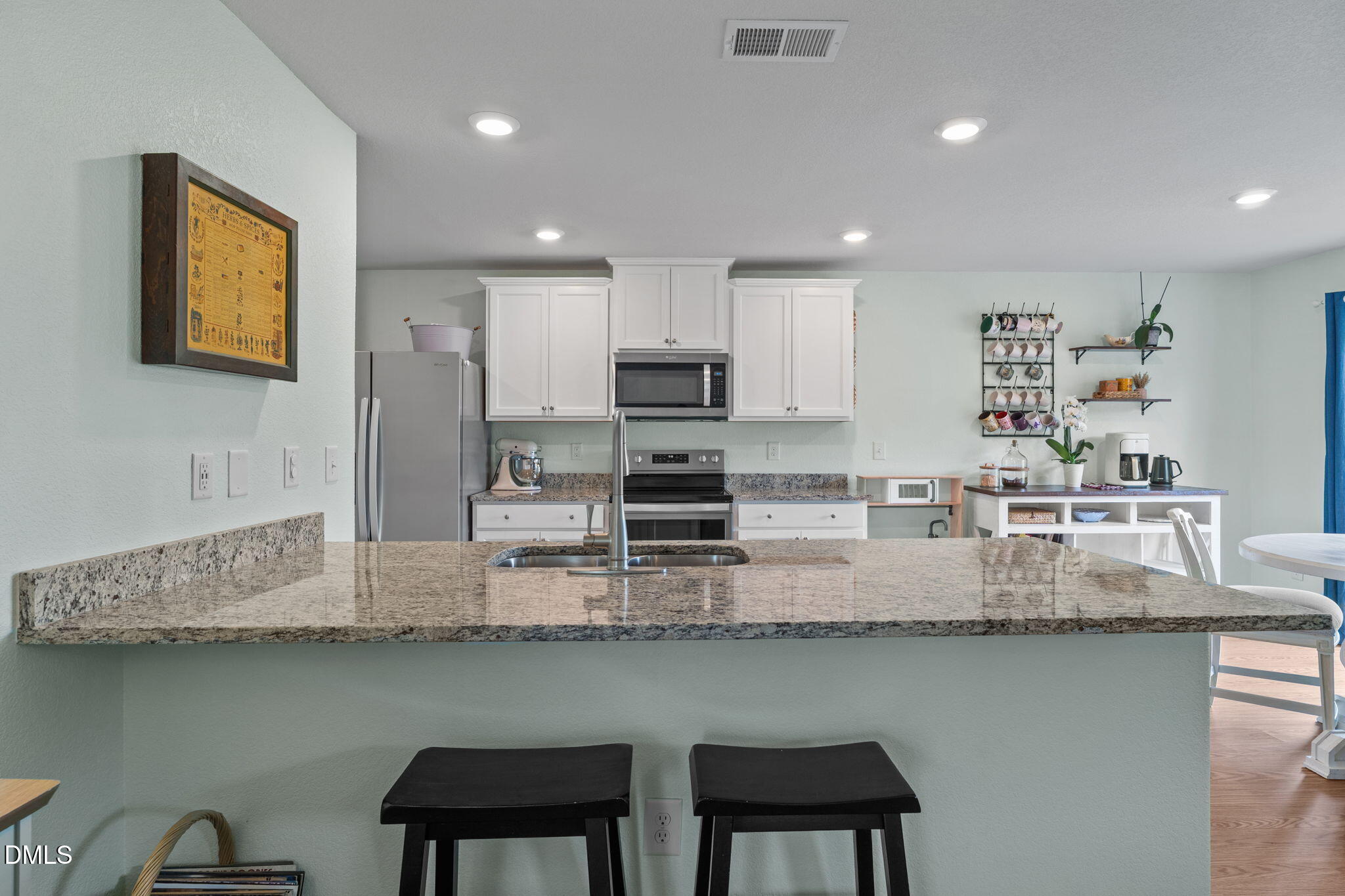 357 Gourd Street Zebulon, NC 27597 - Photo 20 of 50 a kitchen with stainless steel appliances granite countertop a table chairs in it and wooden floors