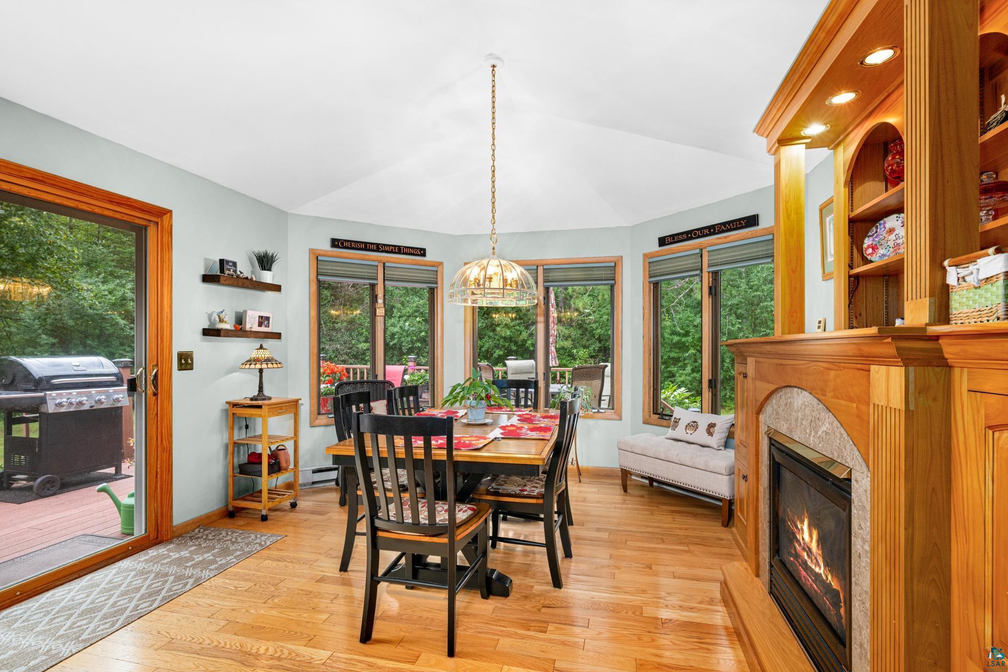 3727 Stebner Road Hermantown, MN 55811 - Photo 16 of 41 Vaulted ceiling, wood-finish flooring, built-in fireplace with stone surround, wood built-in shelving, and multiple windows
