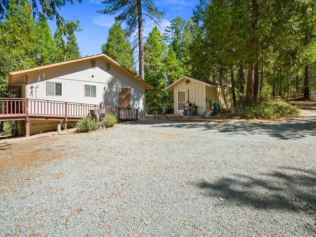 a view of a house with a yard and large trees