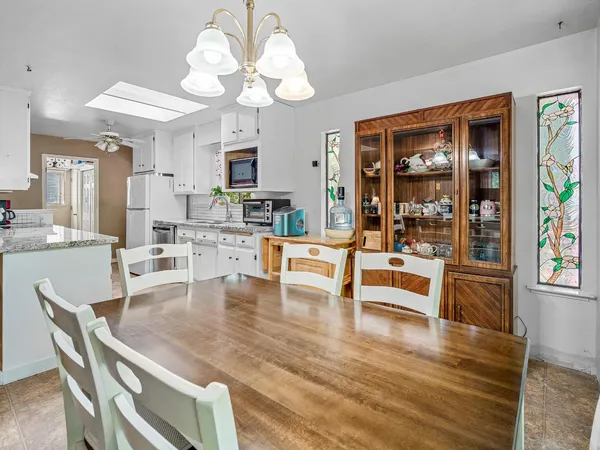 a dining room with wooden floor a chandelier a glass table and chairs