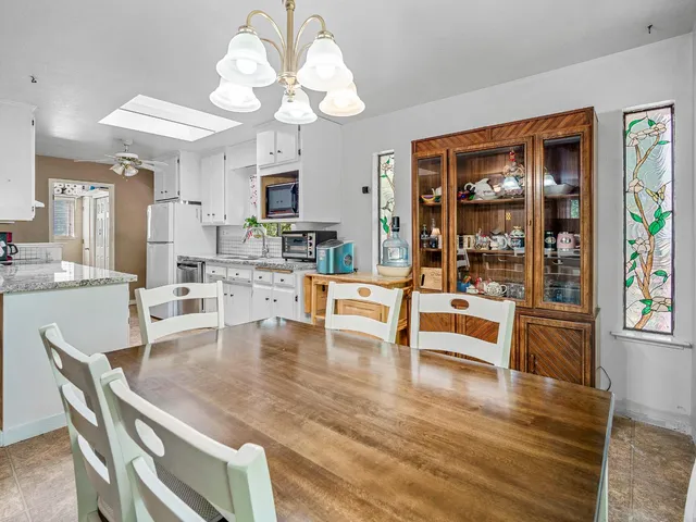 a dining room with wooden floor a chandelier a glass table and chairs