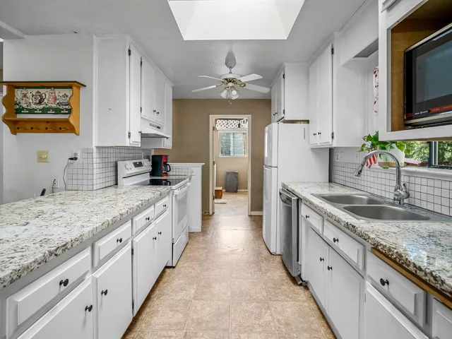 a kitchen with granite countertop a sink stove top oven and refrigerator