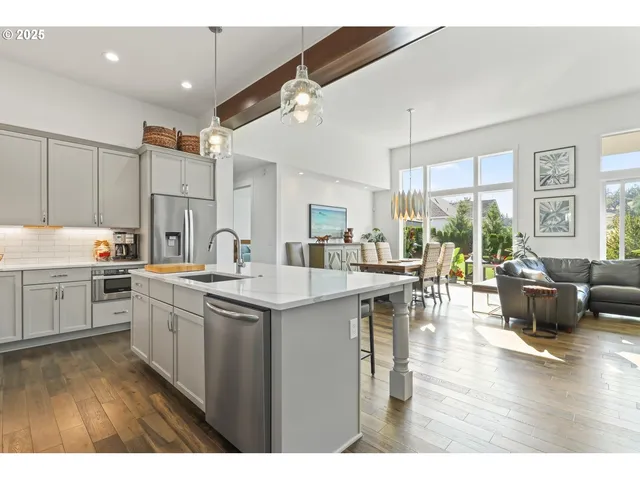 a open kitchen with stainless steel appliances kitchen island granite countertop a sink dishwasher a stove and white appliances with wooden floor