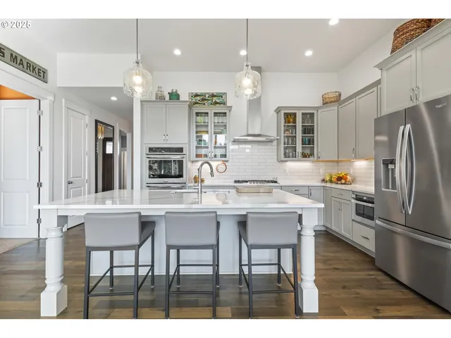 a kitchen with stainless steel appliances kitchen island granite countertop a table chairs sink and cabinets