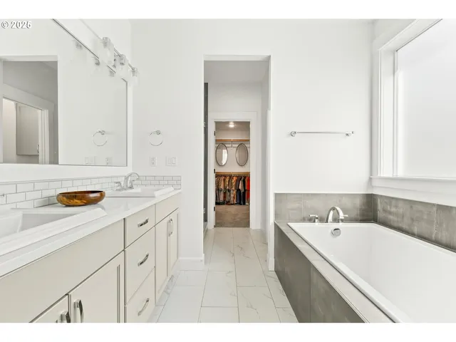 a spacious bathroom with a tub sink and mirror