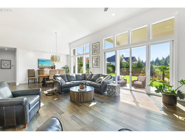 a living room with furniture floor to ceiling window and wooden floor