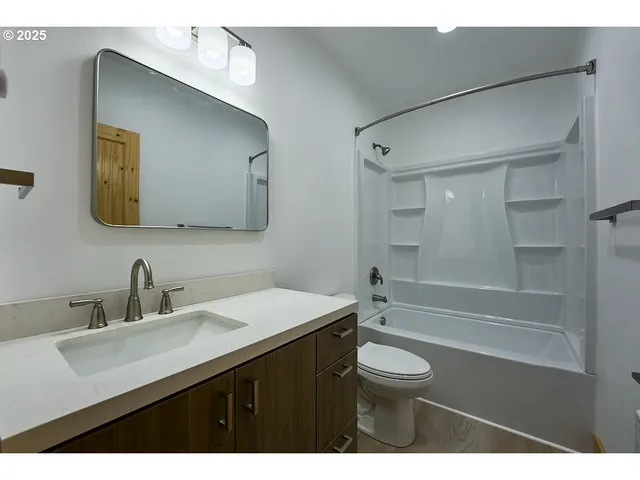 a bathroom with a sink a toilet a mirror and shower