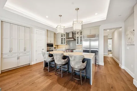 a dining room with stainless steel appliances kitchen island granite countertop furniture and wooden floor