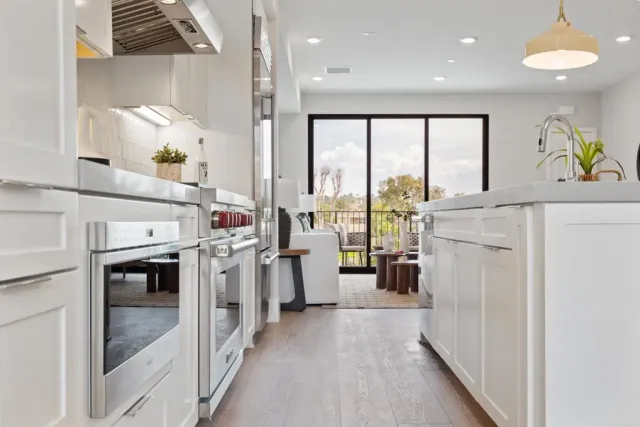 a kitchen with stainless steel appliances a dining table chairs sink and white cabinets