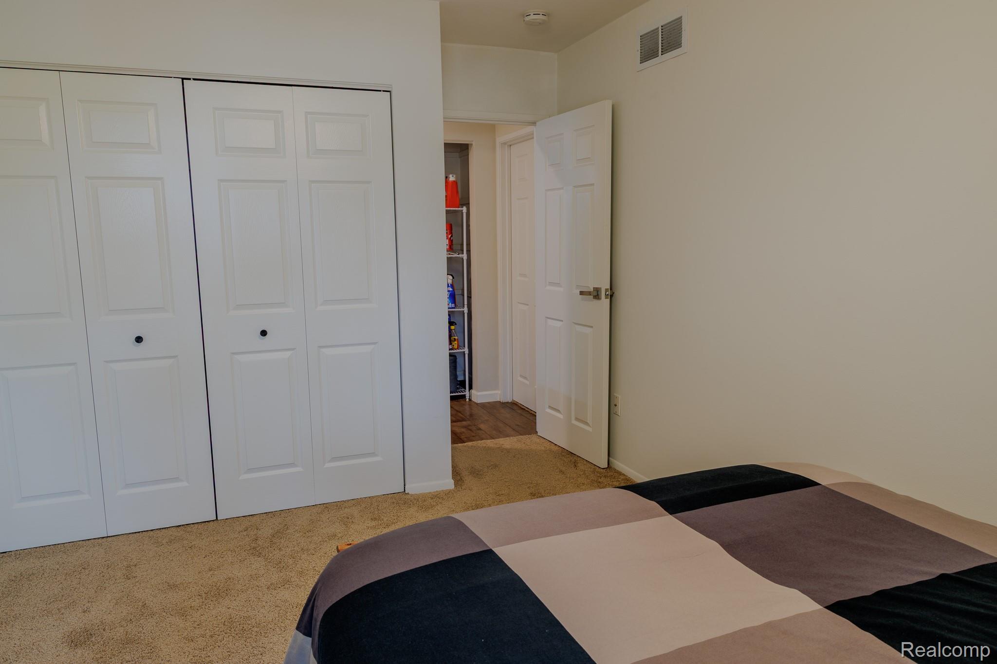 1989 Klingensmith Road, Unit 46 Bloomfield Hills, MI 48302 - Photo 20 of 41 Bedroom featuring bi-fold closet doors with panel detailing, light-toned carpeting, and a white interior door