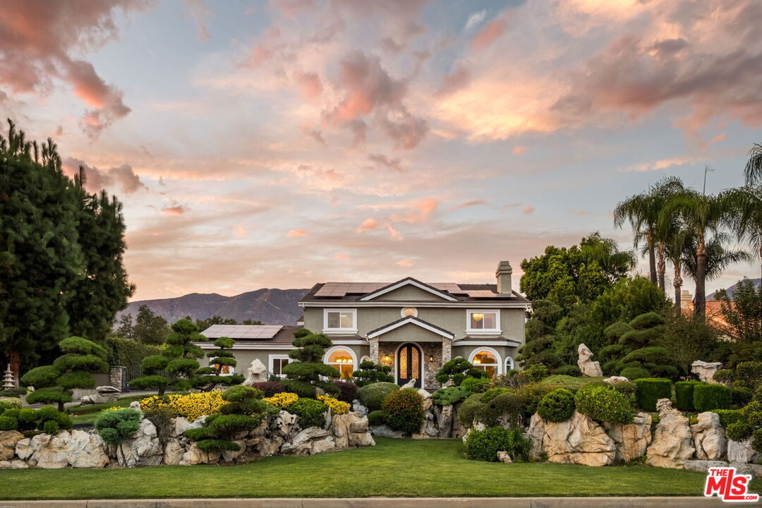 a view of a white house with a big yard and plants