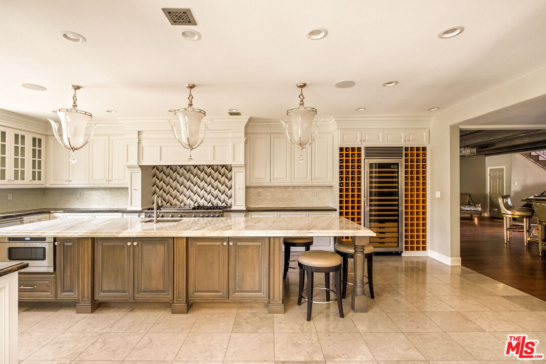 1047 East Pomello Drive Claremont, CA 91711 - Photo 30 of 73 a kitchen with stainless steel appliances kitchen island granite countertop a table chairs and a refrigerator