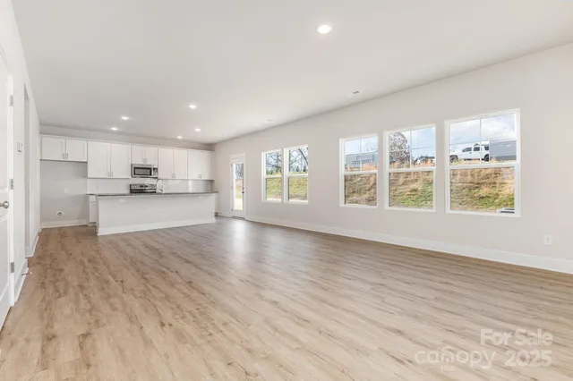 a view of an empty room with window and wooden floor