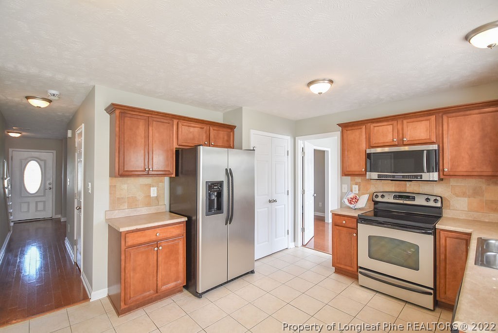 6700 Valley Falls Road Hope Mills, NC 28348 - Photo 13 of 48 a kitchen with stainless steel appliances a refrigerator stove and sink