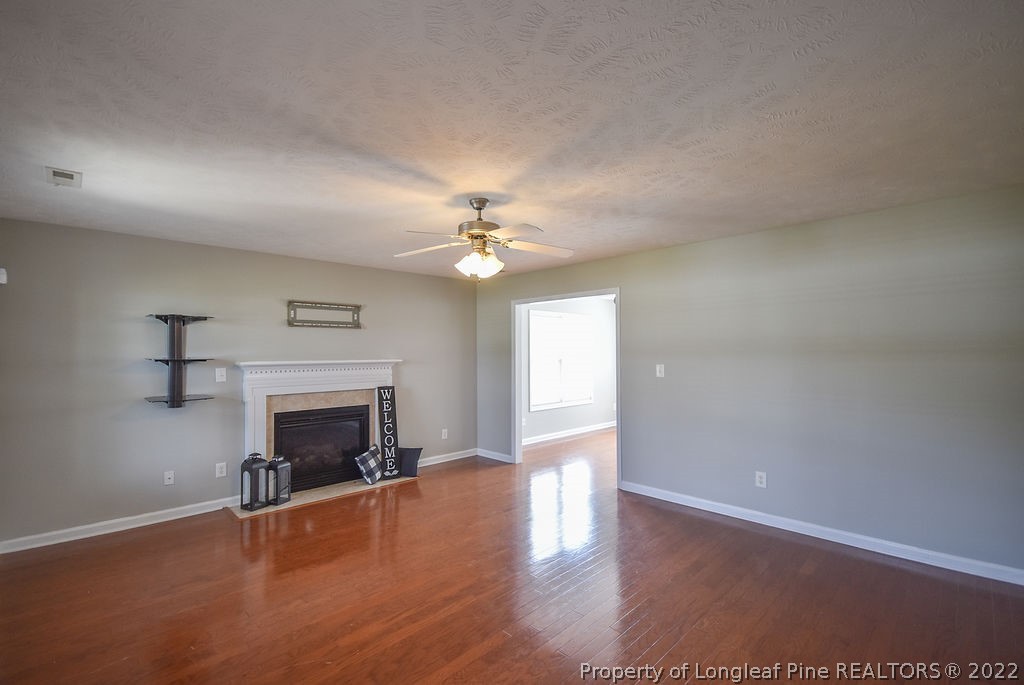 6700 Valley Falls Road Hope Mills, NC 28348 - Photo 7 of 48 an empty room with wooden floor fireplace and windows